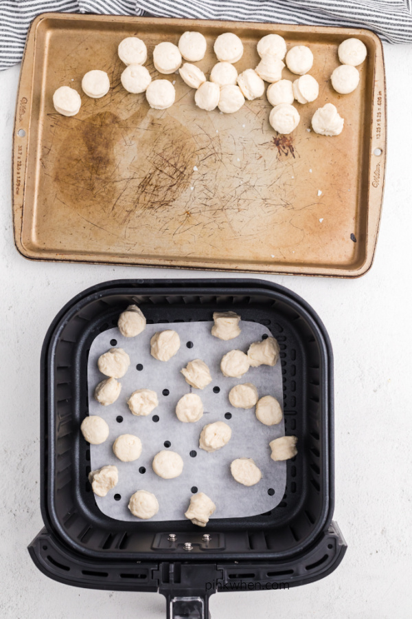 Biscuit dough on parchment paper in an Air Fryer basket. 