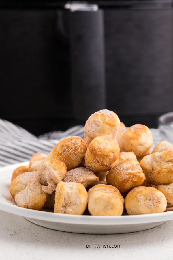 Donut holes on a plate in front of an Air Fryer.