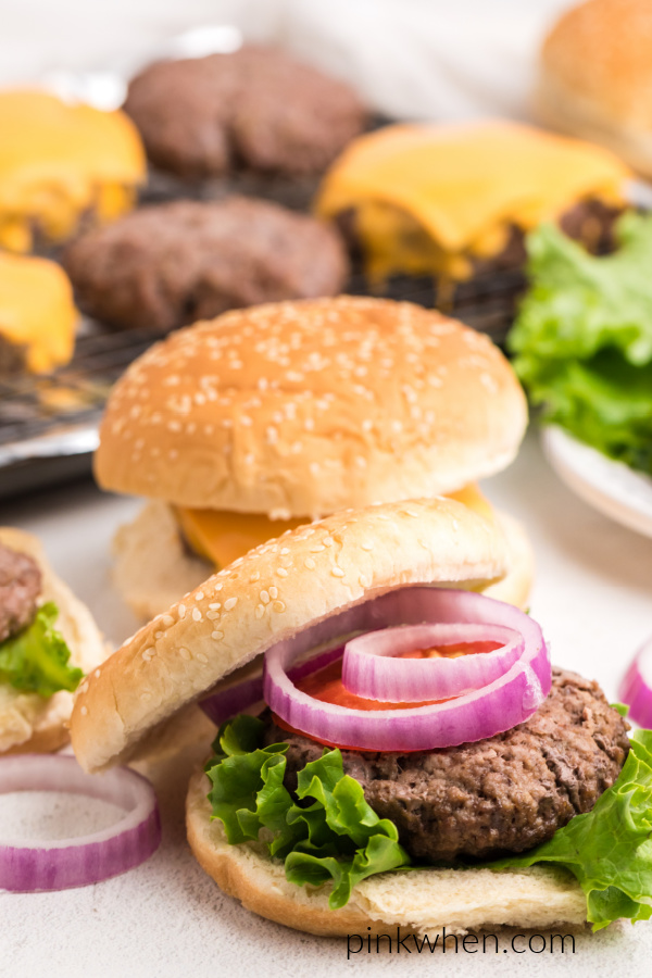 Baked hamburger on a bun with lettuce, tomato, and onion.