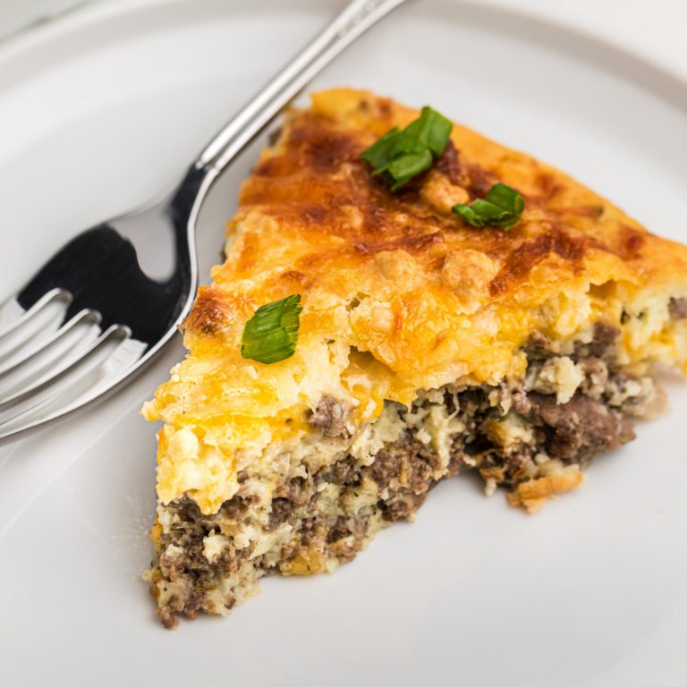 Slice of cheeseburger pie on a white plate with a fork
