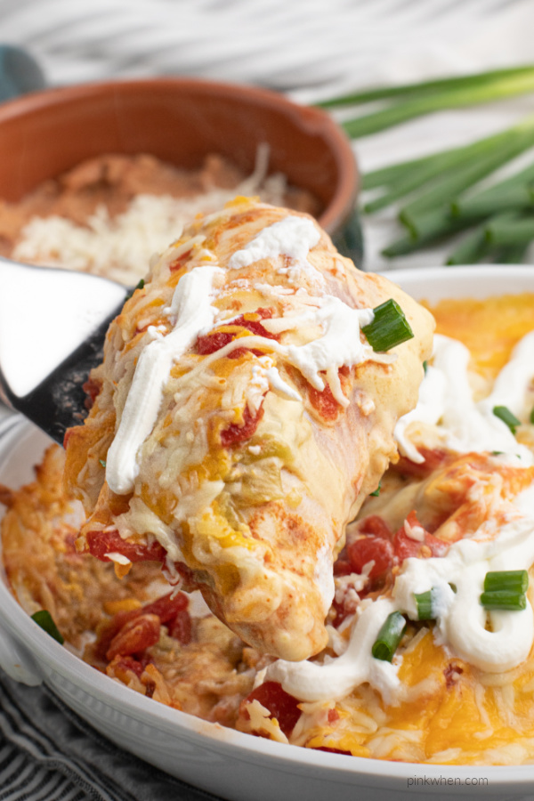 Taco casserole made with chicken being scooped from a white casserole dish. 