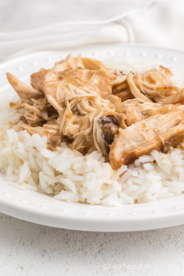 Crockpot Chicken and Gravy served over white rice on a white plate. 