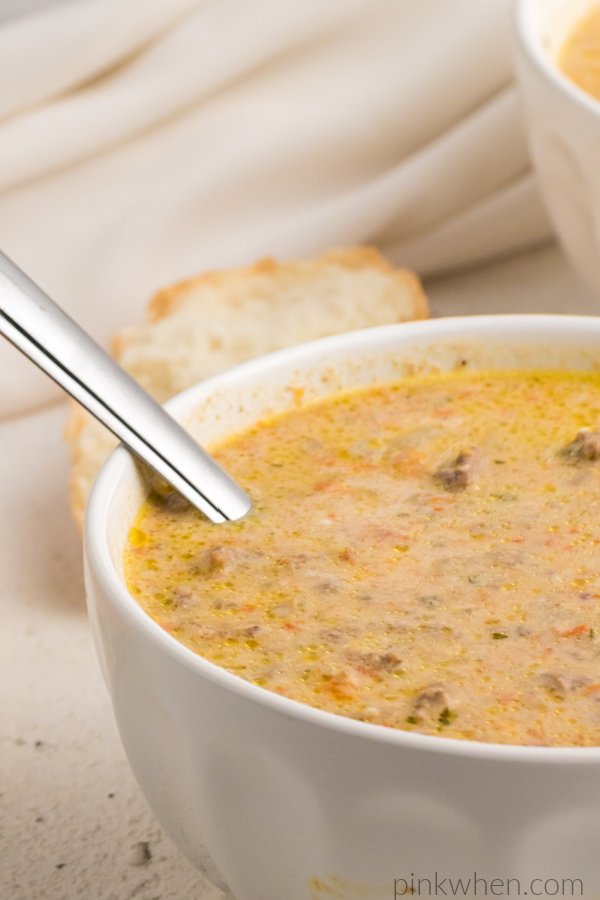 Cheeseburger soup in a white bowl with a spoon and ready to eat.