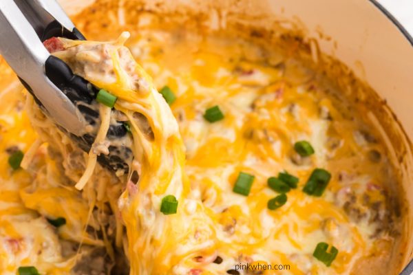 Taco Spaghetti being picked up with tongs to show cheesy noodles. 