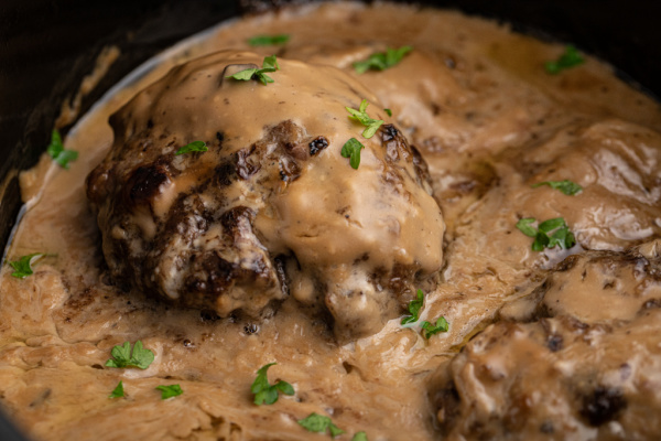 Salisbury Steak in Slow Cooker with parsley sprinkled on top.