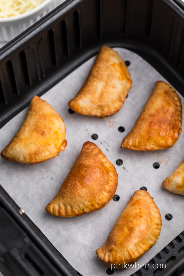 Pizza rolls in the basket of the Air Fryer on parchment paper. 