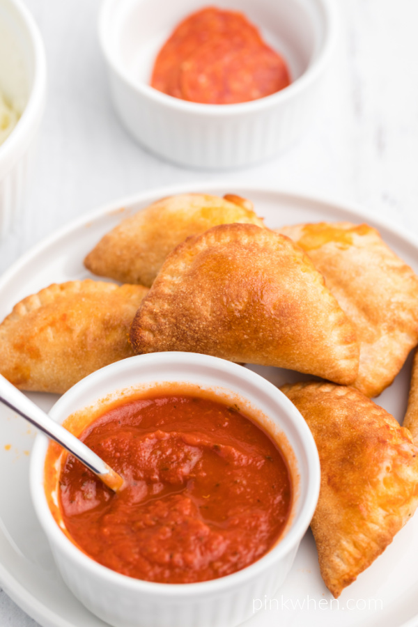 Homemade Pizza Rolls on a white plate with extra pizza sauce for dipping.