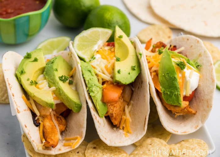 Air Fryer chicken fajitas topped with sour cream, cheese, and avocado slices ready to eat. 
