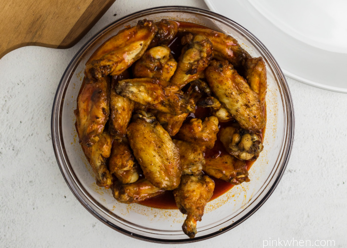 Cooked wings getting tossed in barbecue sauce before serving. 