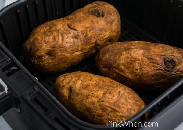 Baked potatoes fully cooked in an air fryer basket. 