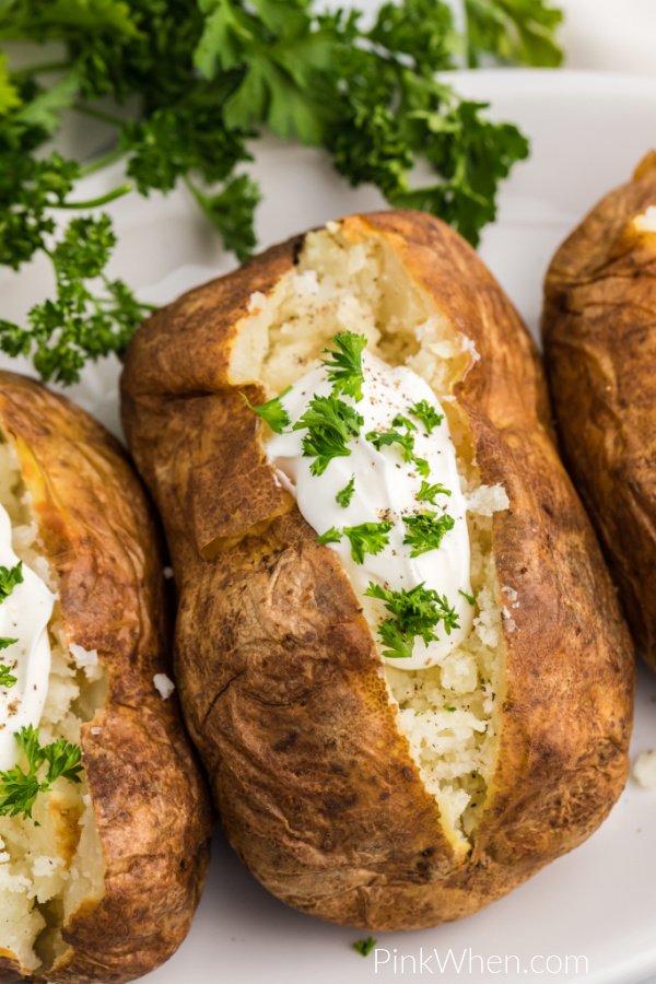Air Fryer Baked Potatoes are topping with sour cream and fresh parsley and ready to eat! 