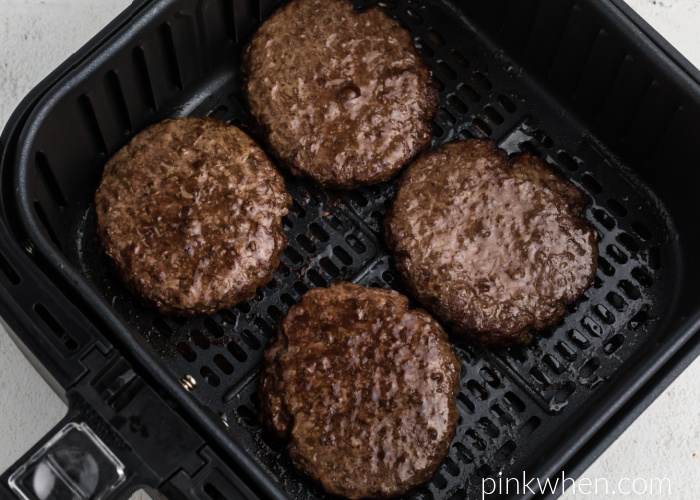 Fully cooked Air Fryer burgers in the basket of the Air Fryer. 
