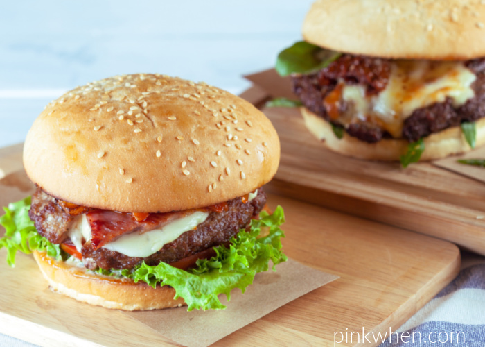 Fully dressed hamburgers with all the fixings on cutting boards and ready to serve. 