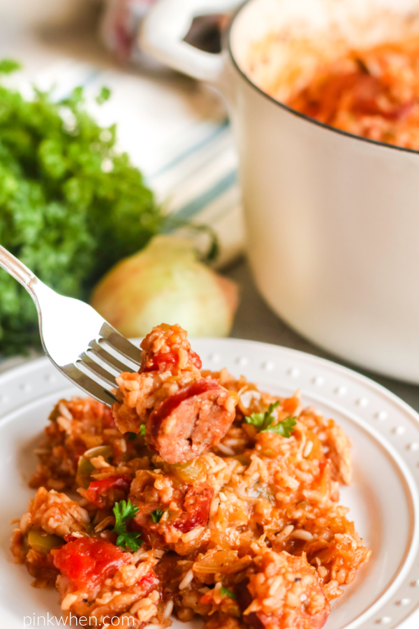 Chicken jambalaya on a white plate with a bite ready to eat. 