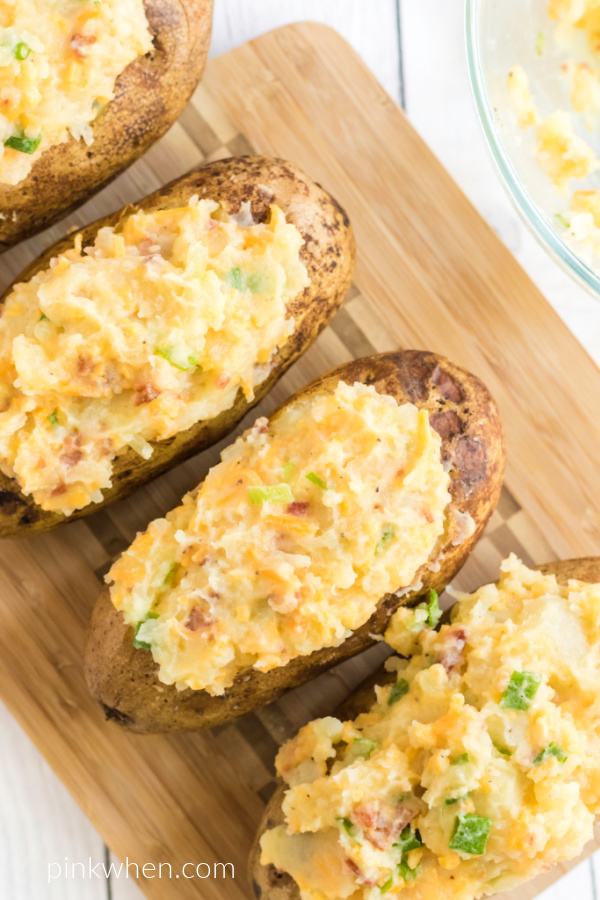 Overhead photo of twice baked potatoes on a cutting board, ready to serve.