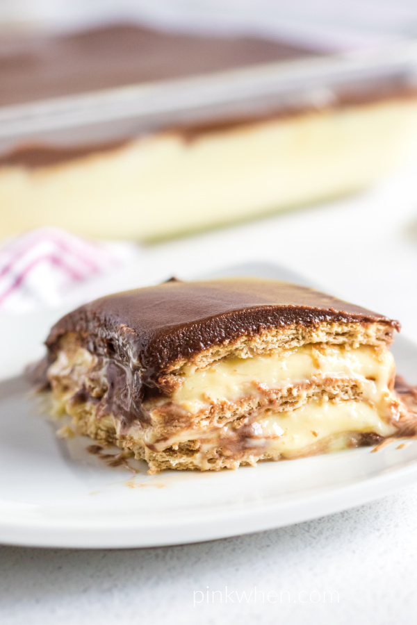 Slice of no bake chocolate eclair cake on a white plate ready to eat. 