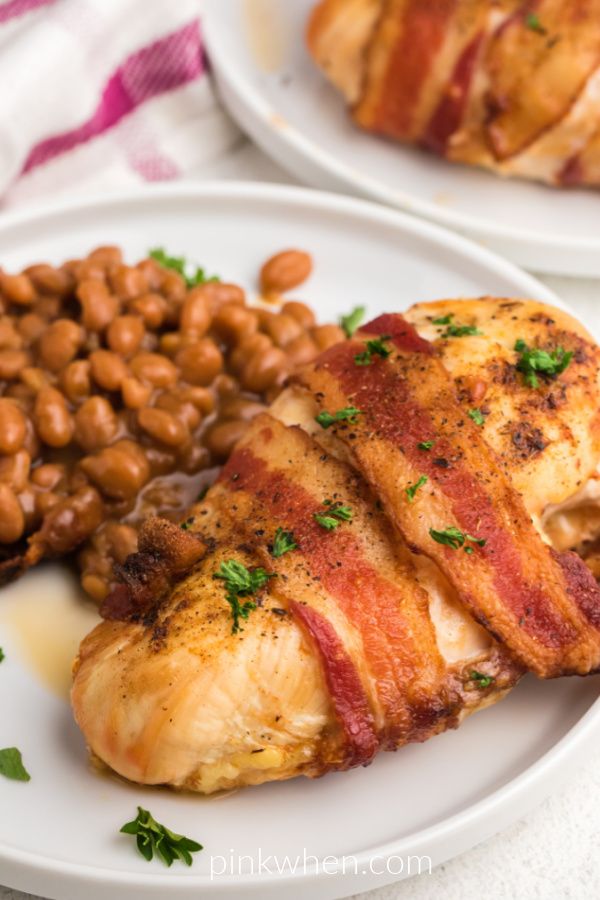 Air Fried Bacon Wrapped Chicken on a white plate with a side of beans. 