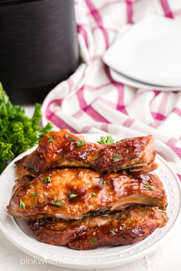 Air Fryer Country Style Ribs on a white plate smothers with barbecue sauce and topped with fresh parsley. 
