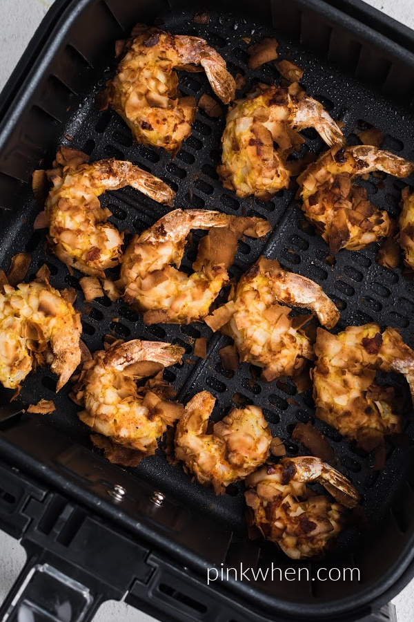 Coconut shrimp in the air fryer basket fully cooked. 