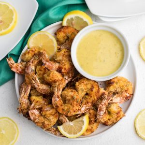 Air Fryer Fried Shrimp with lemon slices and serving sauce on a white plate.