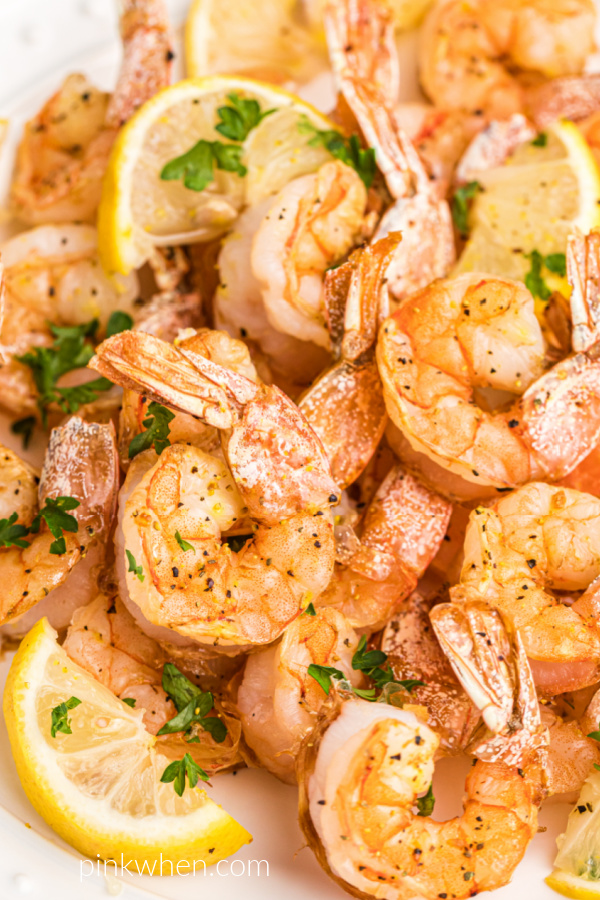 Air Fryer Lemon Pepper Shrimp fully cooked and on a white plate with lemon wedges and fresh parsley. 