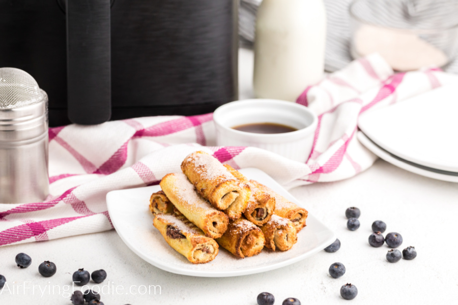 Air Fryer Nutella French Toast Roll Ups on a white plate and dusted with powdered sugar. Ready to eat! 