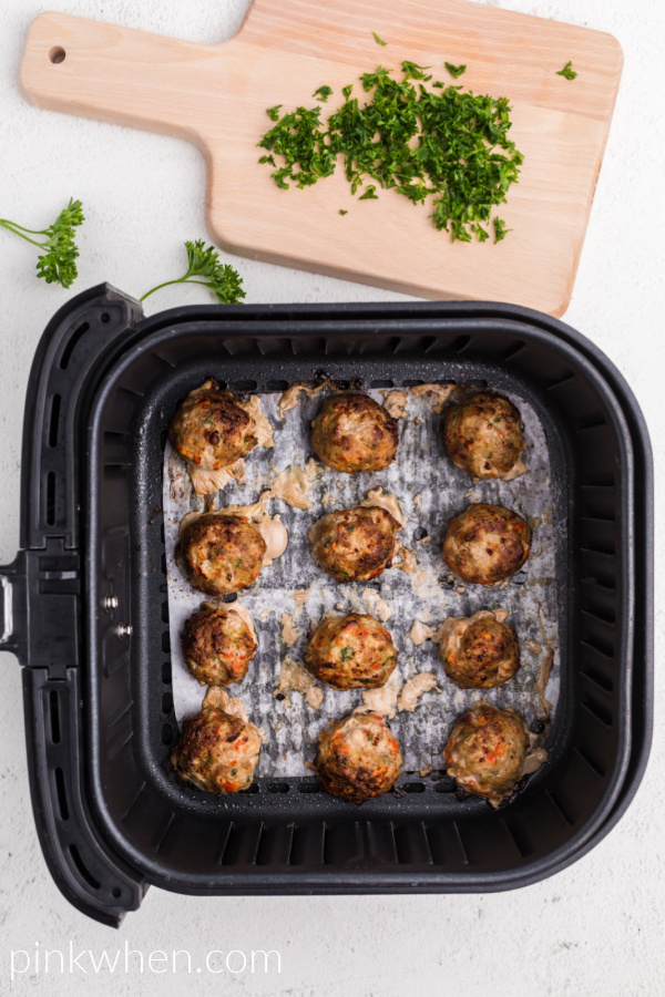 Turkey meatballs cooked and ready to serve in the basket of the air fryer. 