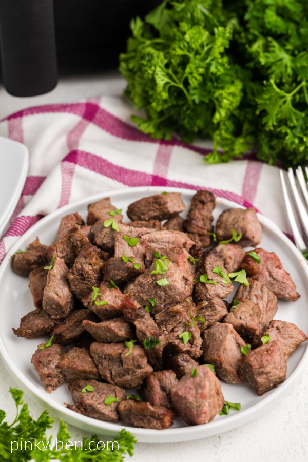 Air Fried Garlic Butter Steak Bites on a white plate and garnished with fresh parsley. 