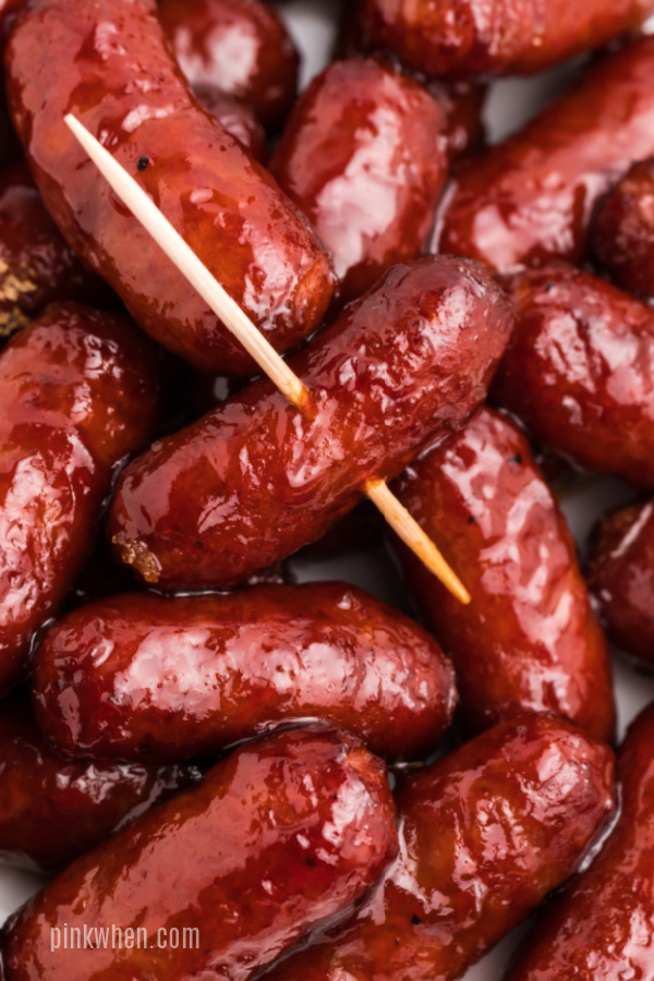 Close up photo of BBQ lil smokies on a white plate - one with a toothpick inserted through it. 