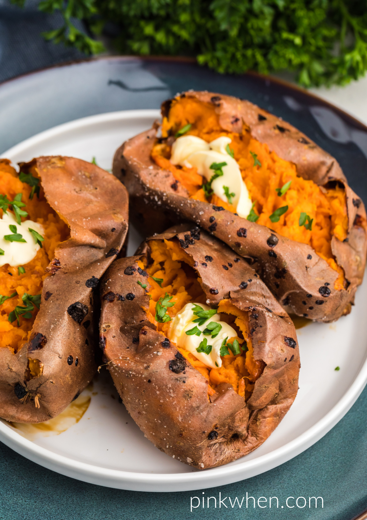 Air Fried Sweet Potatoes on a plate topped with butter and fresh parsley. 