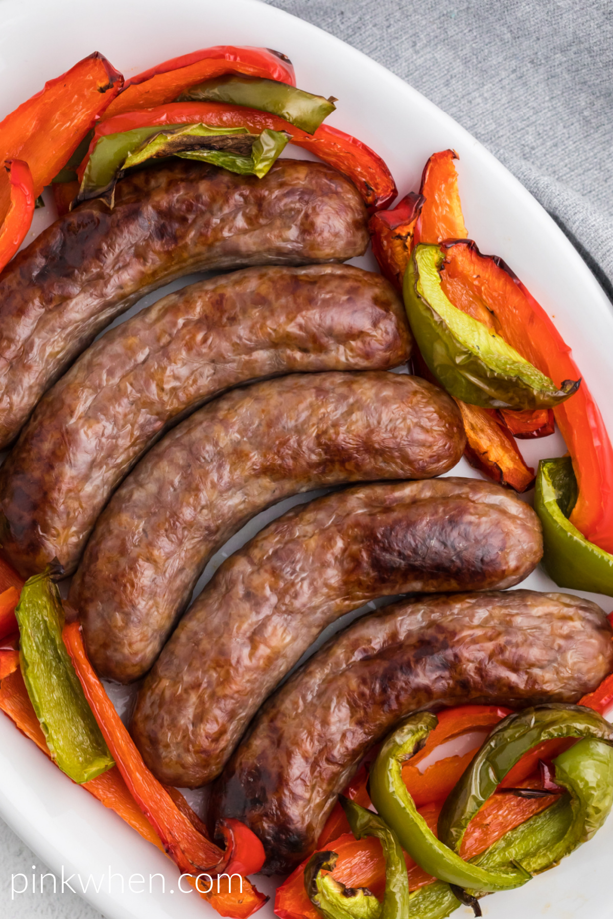 Brats made in the air fryer with bell peppers - served on a white serving dish. 