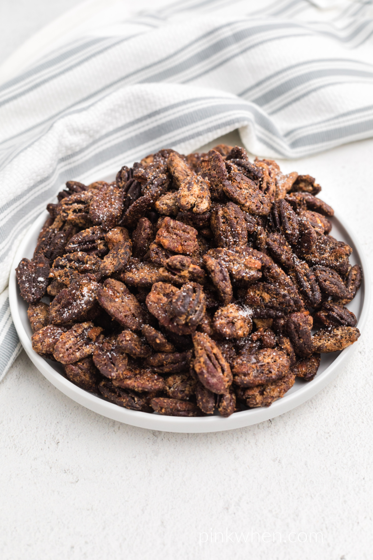 Candied pecans made in the air fryer, on a white plate ready to eat. 