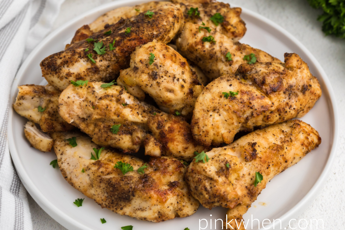 Air Fried Grilled Chicken Tenders garnished with fresh parsley on a white plate ready to serve.
