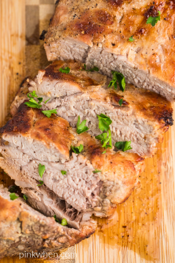 Air Fried Pork Tenderloin on a cutting board - cut into medallions and topped with fresh chopped parsley. 