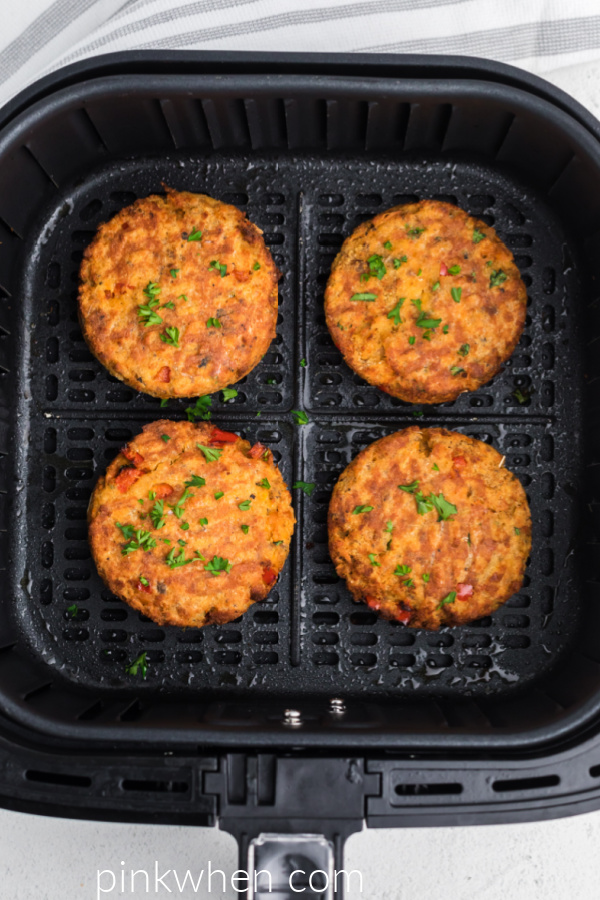 Fully cooked salmon patties in the basket of the air fryer. 