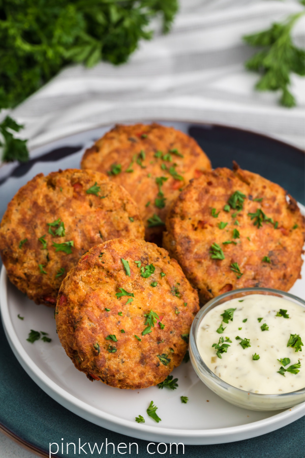 Air Fried Salmon Patties on a white plate with blue charger and tarter sauce on the side. 