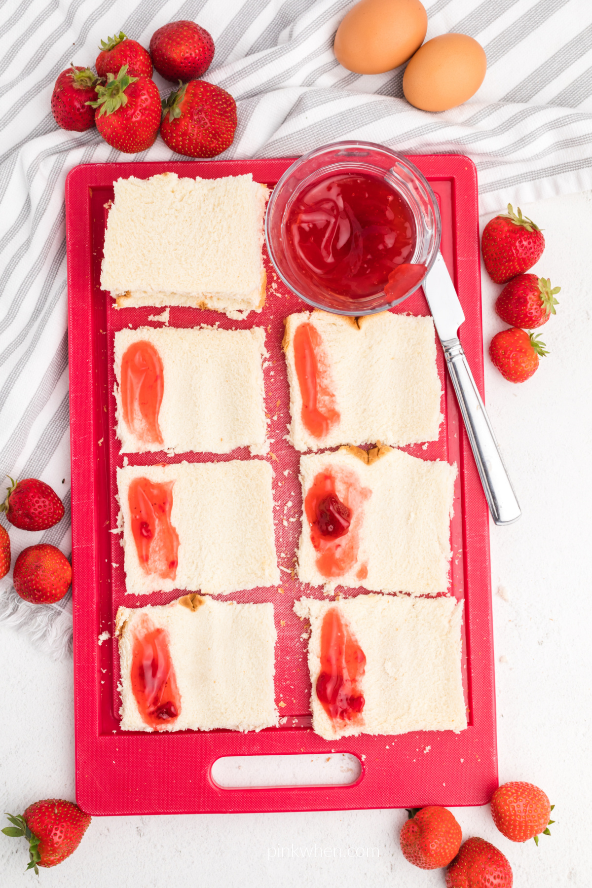 Process photo of strawberry preserved on bread ready to be made into french toast roll ups. 