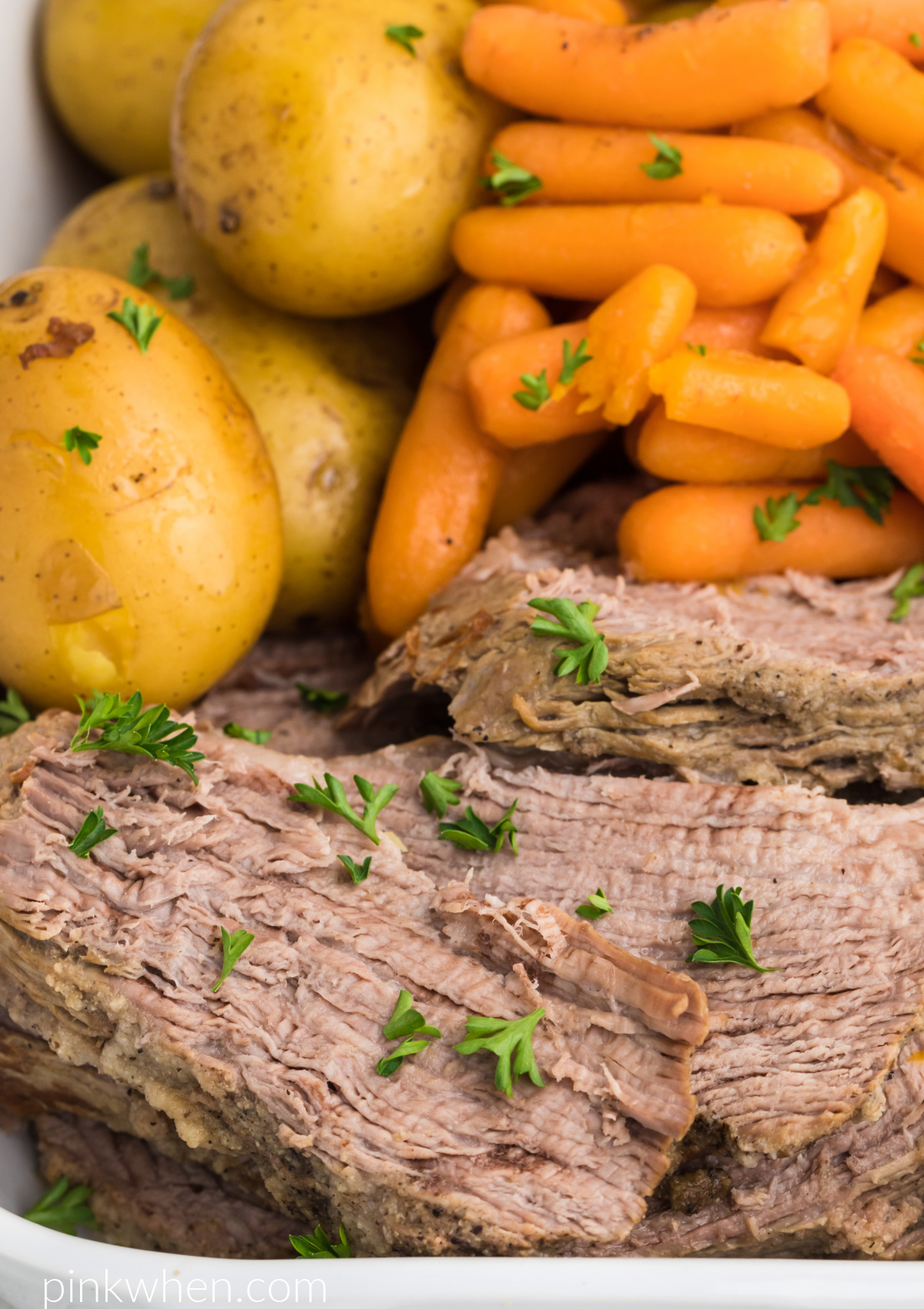 Instant Pot Tri Tip roast sliced and served with vegetables and garnished with fresh parsley. 