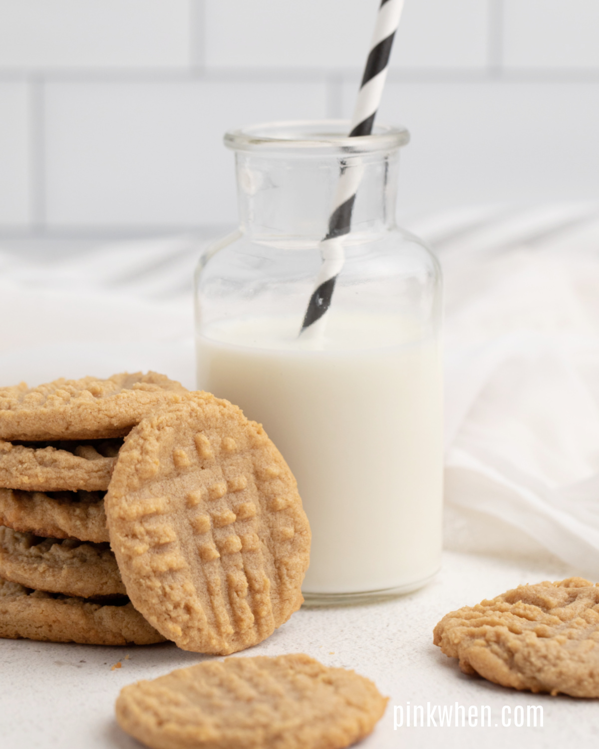 3 Ingredient Peanut Butter Cookies on a white table with a glass of milk. 