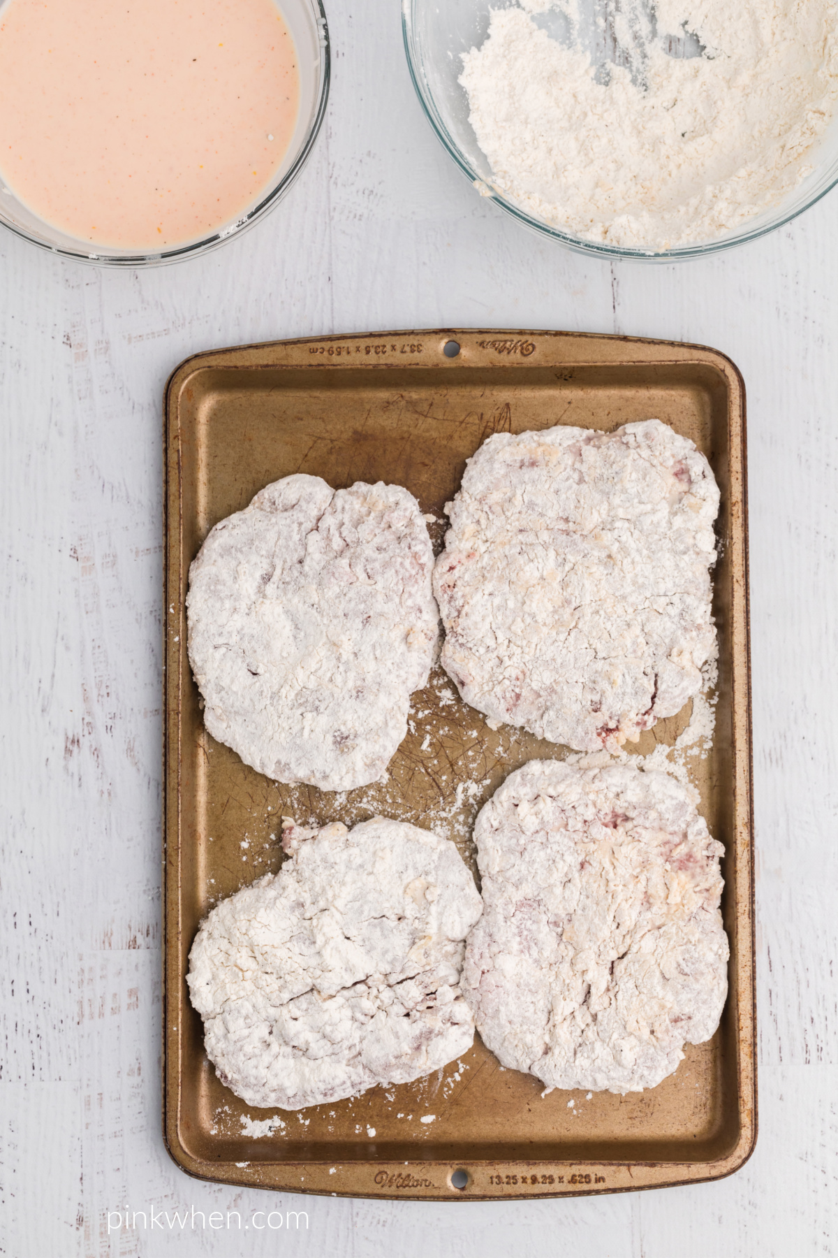 Cubed steaks dredged in flour and egg mixture and placed on a baking sheet.