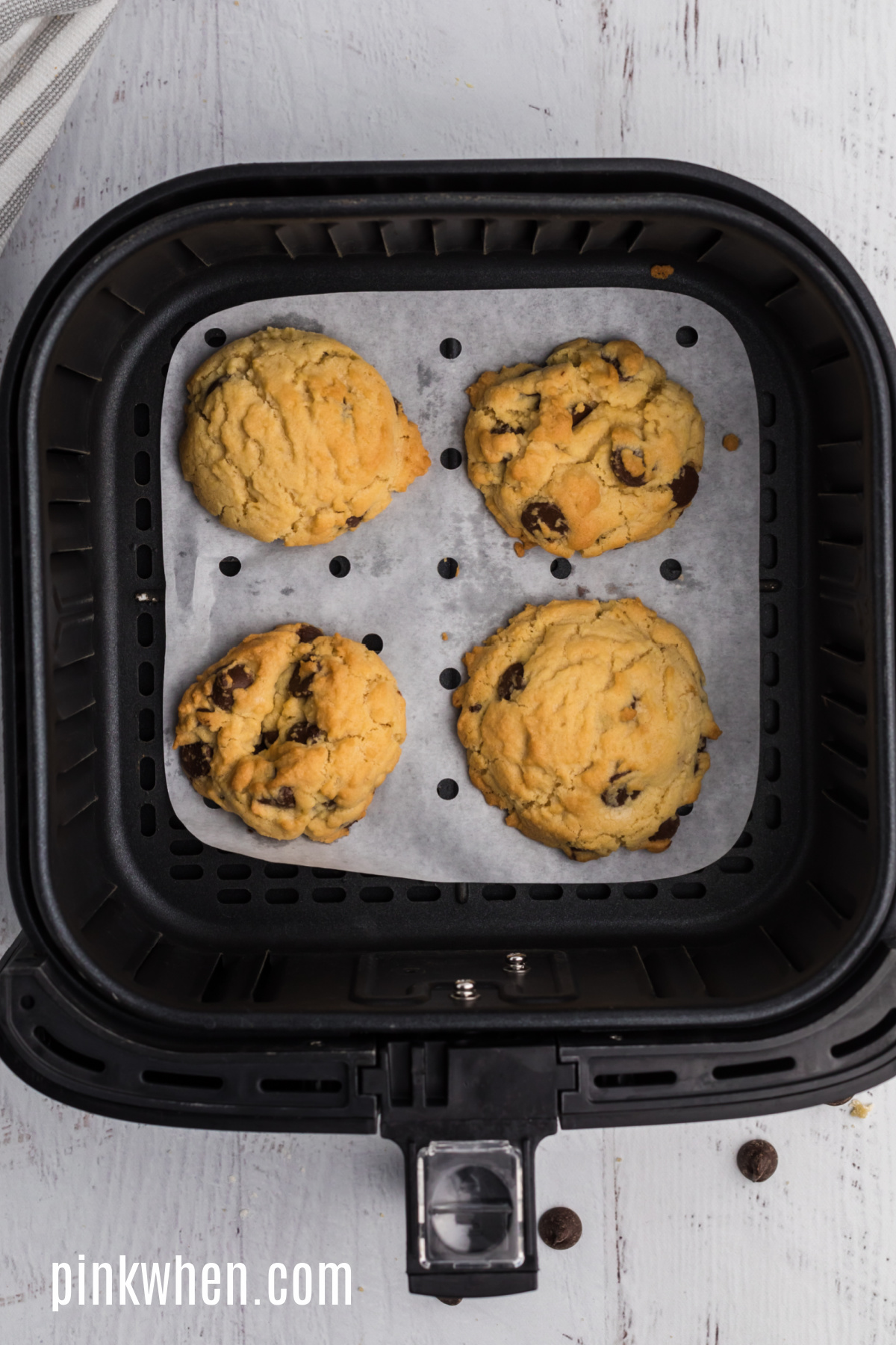 Larger sized Chocolate chip cookies in the basket of the air fryer.