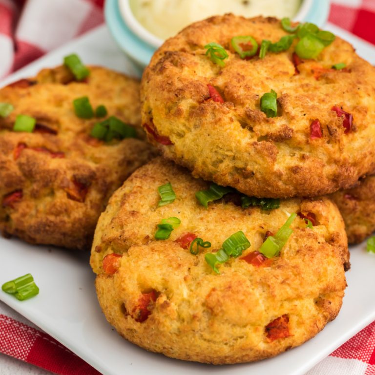 Crab cakes on a plate topped with fresh green onion tops.