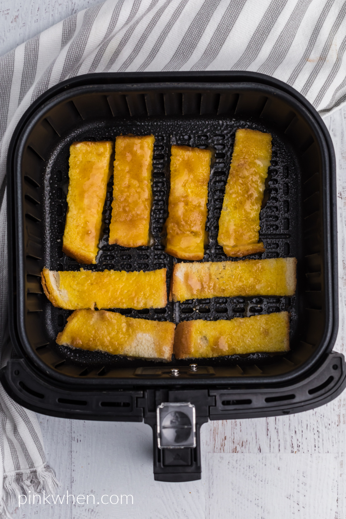 French toast sticks in the basket of the air fryer ready to be cooked. 
