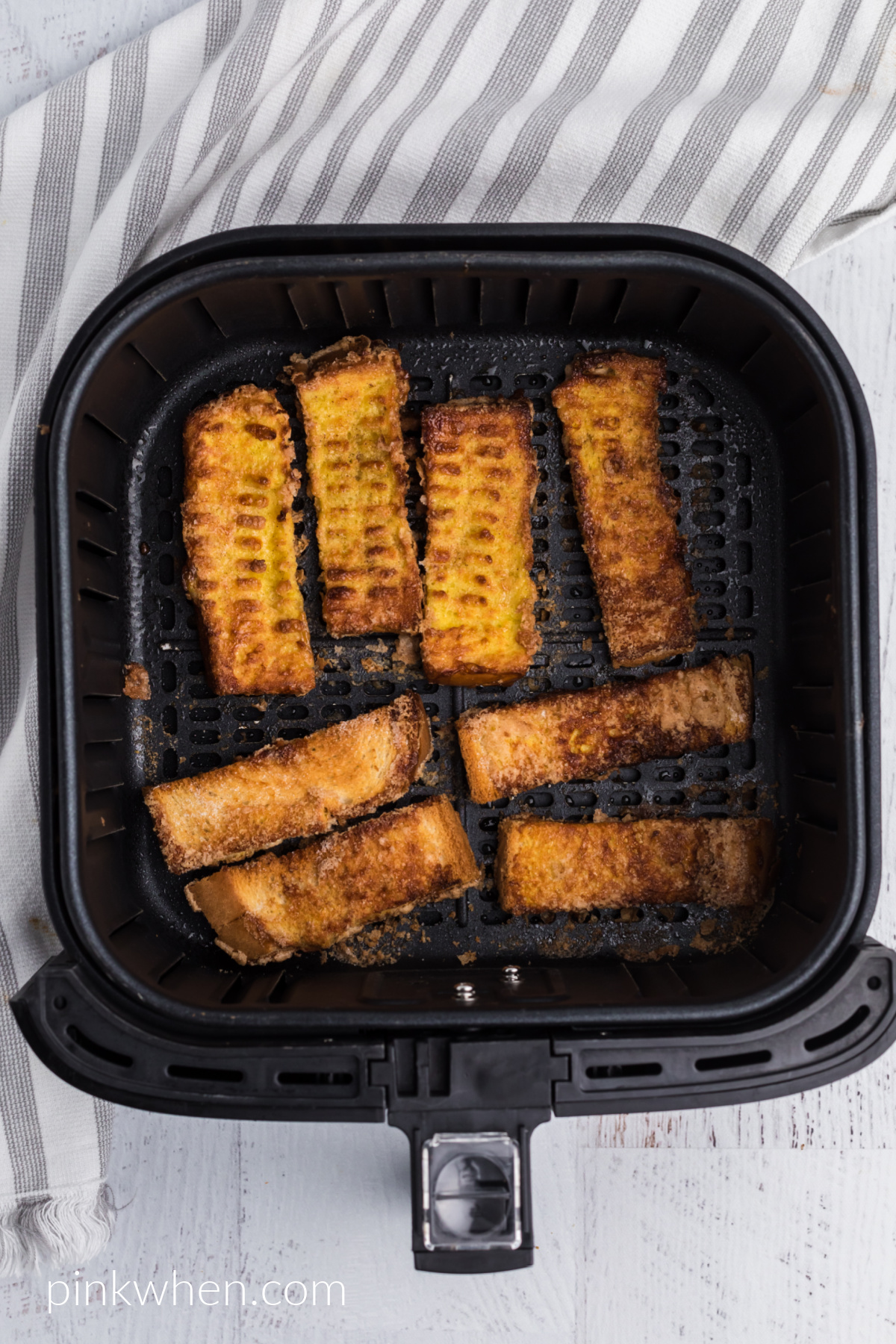 cooked french toast sticks in the air fryer basket.