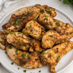 Overhead view of air fryer grilled chicken tenders on a white plate ready to serve.