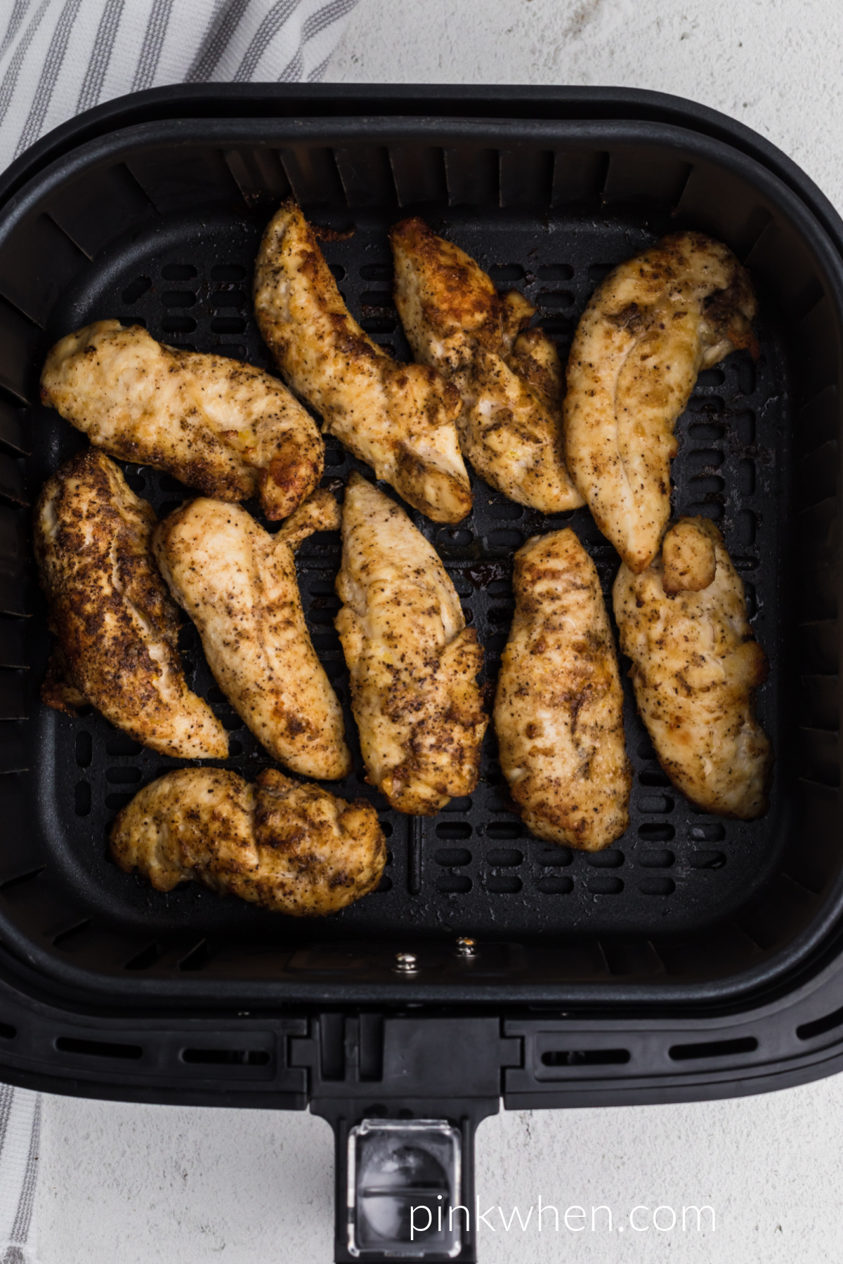 Grilled chicken tenders in the basket of the air fryer. 