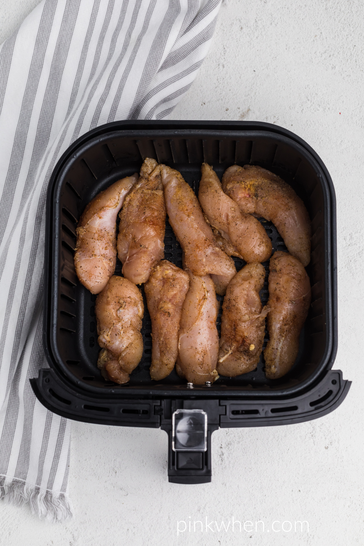 chicken tenders in the air fryer basket ready to be cooked.