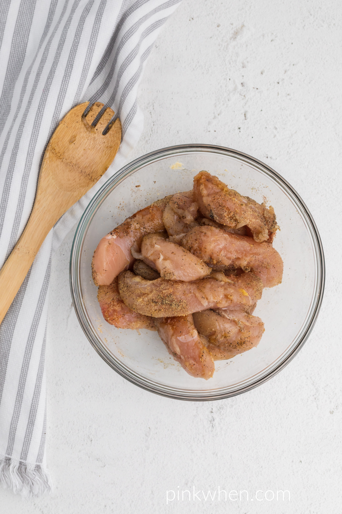 oiled and seasoned chicken tenders in the mixing bowl ready to be grilled in the air fryer. 