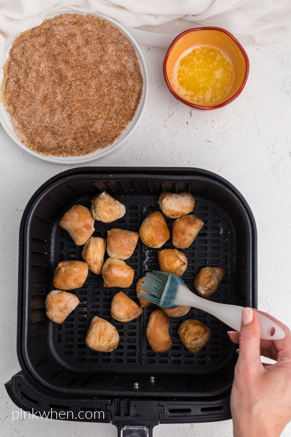 Brushing butter on pretzel bites before dipping into cinnamon and sugar. 