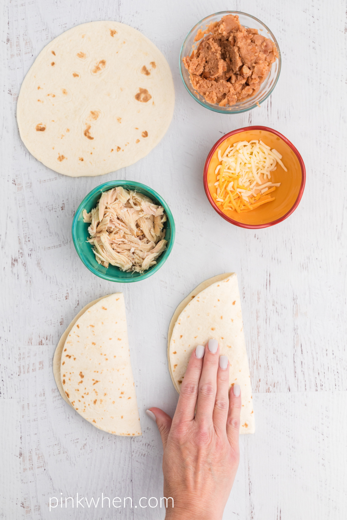 Hand folding over quesadillas before placing them into the air fryer. 